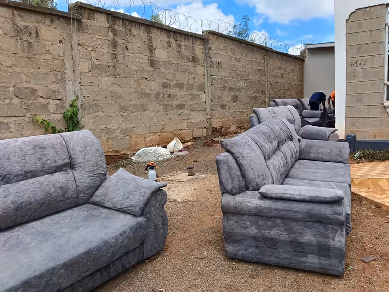 Multiple grey fabric sofas laid outside for a bulk upholstery cleaning job in Nairobi