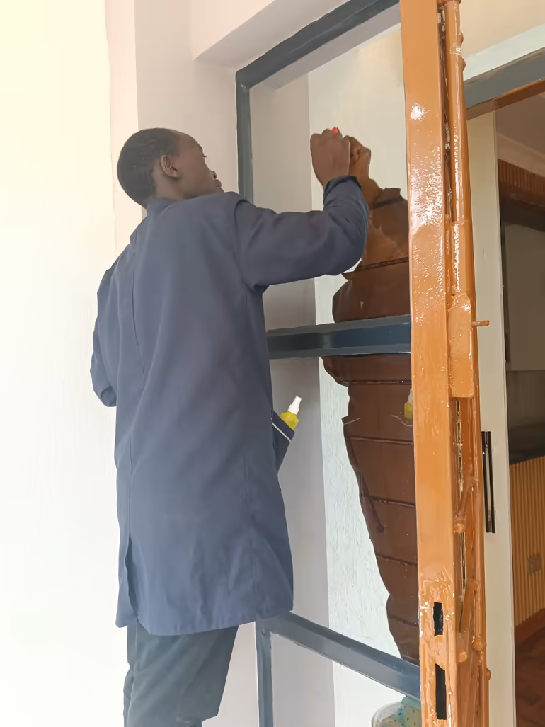 Shine On cleaner detailing a metal door fixture during a home cleaning in Kiambu